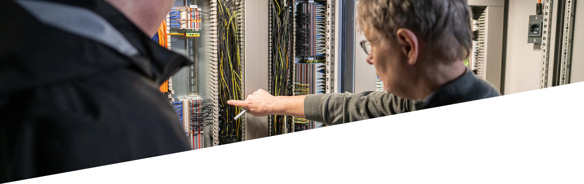 GMSH-Ausbilderin erklärt einem Studi die Elektroverkabelung im Schaltschrank.